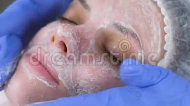 美容师将面膜卷在女人`面部按摩动作上。 美容师面部治疗。 特写镜头。
